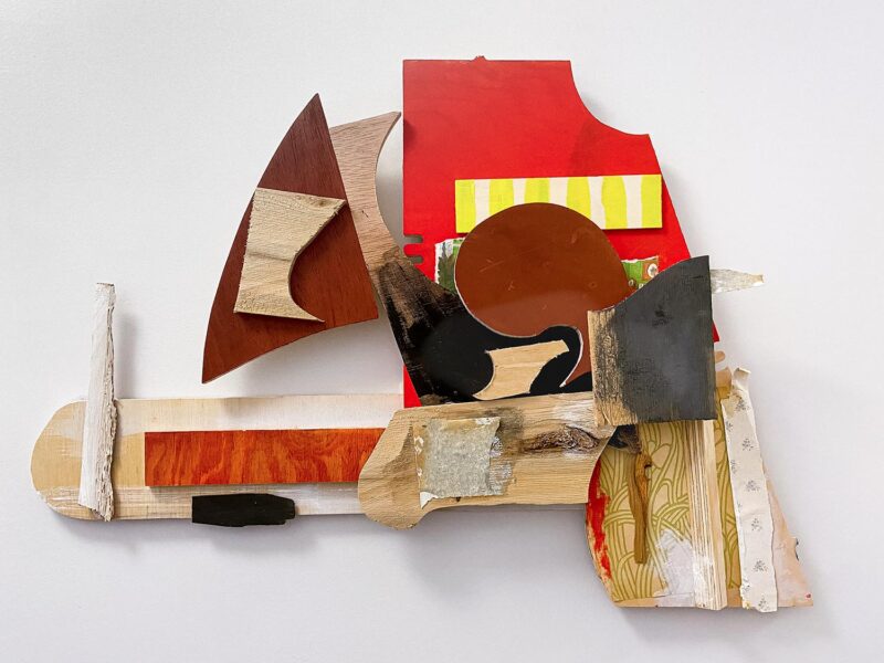 Abstract wall sculpture made of red and natural pieces of plywood.