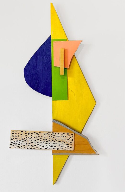 Abstract wall sculpture made of yellow and blue pieces of plywood.