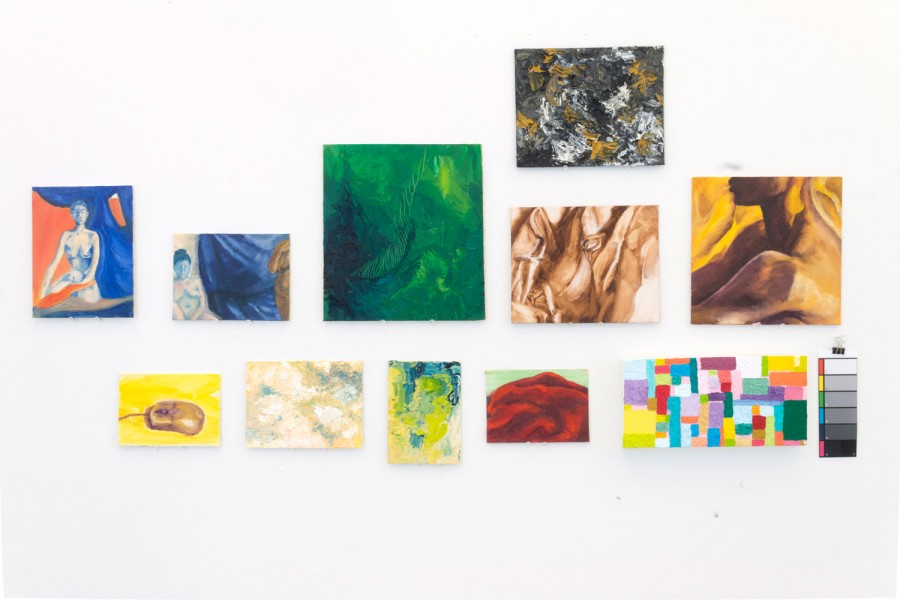 Exhibition view of abstract paintings and portraits arranged randomly on the wall
