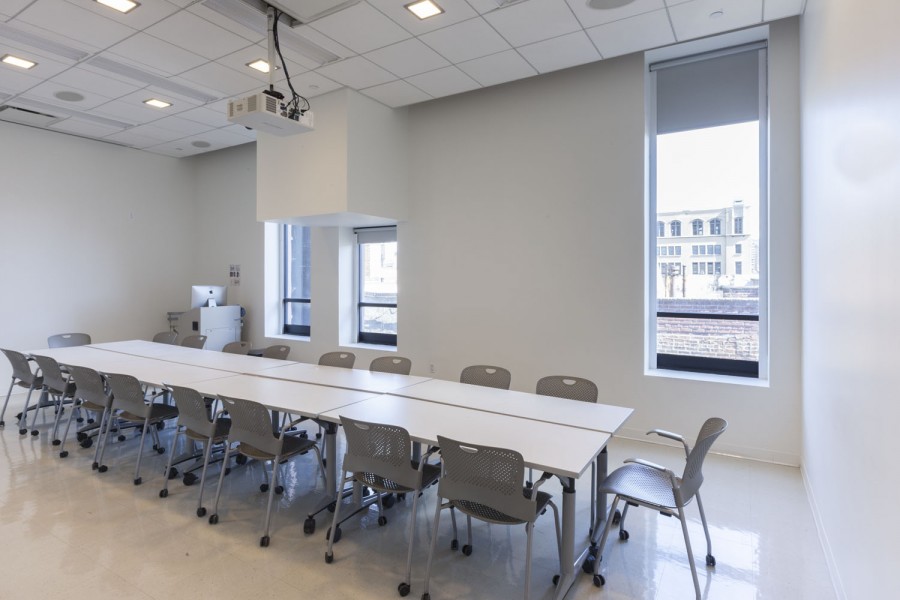 Conference room with a long table and chairs, an image projector and three windows