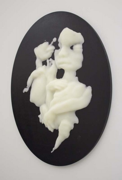 A sculpture made from a white organic material with rounded and curved shapes, on a black oval