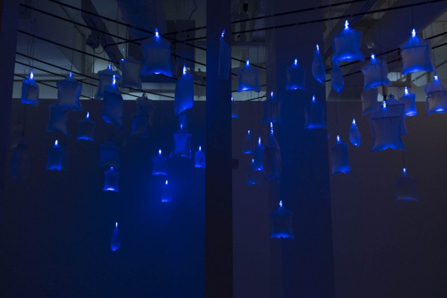Many water bags hanging on the ceiling with small blue light illuminating them