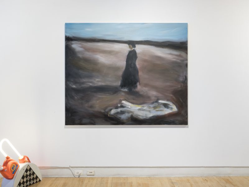 Install shot of painting on a wall, painting of a woman in a desolate landscape.