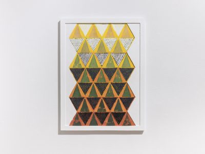 Install shot of a black, yellow, and orange triangle painting. 