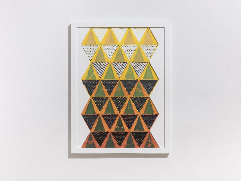 Install shot of a black, yellow, and orange triangle painting.