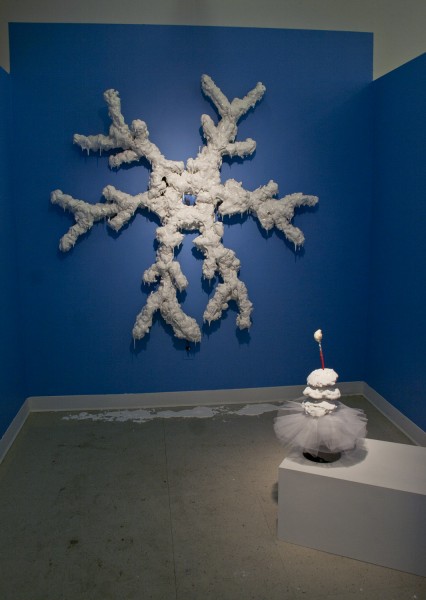 Sculpture hung on a blue wall in the shape of a snowflake.  
