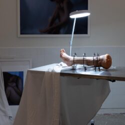 Installation shot of a replica leg in a leg brace on an aluminum surgeons table with a bright lamp.