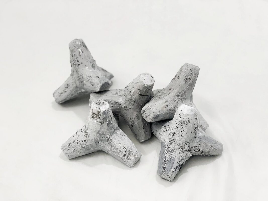 Five tetrapods stacked on the ground made of grey plaster.