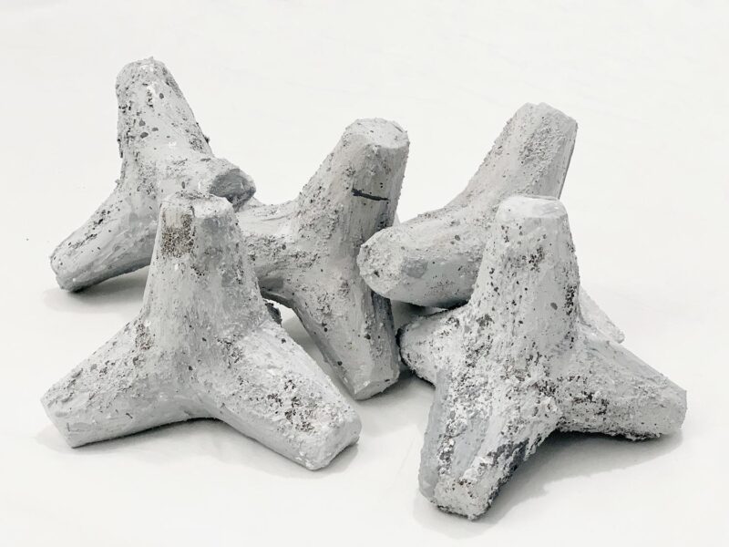 Five tetrapods stacked on the ground made of grey plaster.