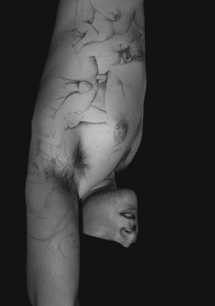 Black and white photograph with a black background and a naked torso with a black and white image projected on top of the person of male genitalia.