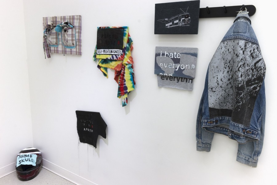 Installation view of a jacket hung on the wall, prints, etc,
