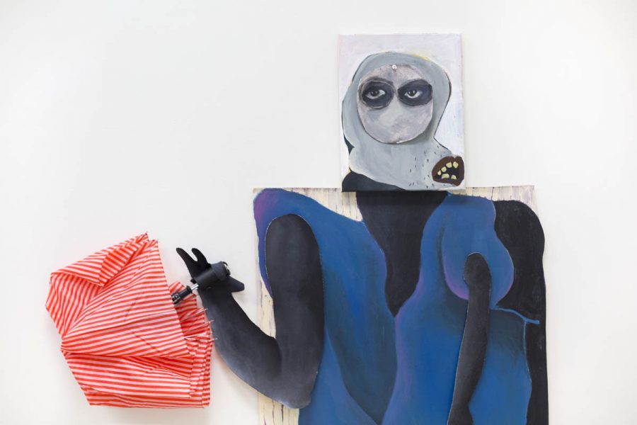 Composite artwork made of painted canvas is constructed to form a silhouette with blue clothes, a white hood on the head with only eyes visible, and a red umbrella in the left hand. the work is installed on the wall