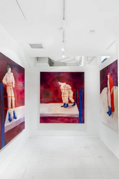 Exhibition view of Three large-scale paintings with a nude man fighting in a battle ring with a red background