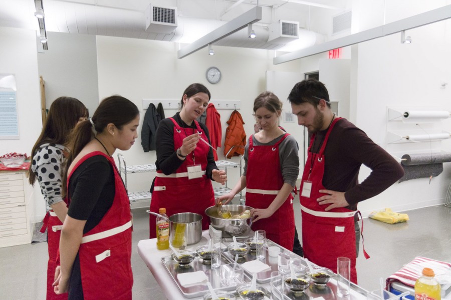 Students with red aprons around the table working with organic materials and a table full of many objects.