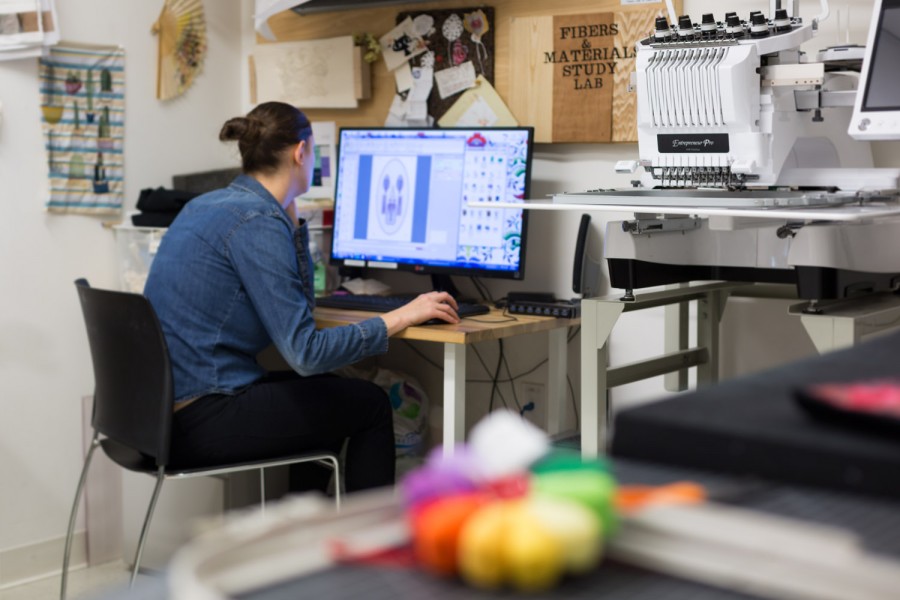Student working on an embroidery design on a computer in Fabrics studio