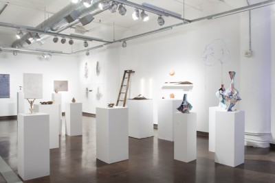 Installation view of sculptures placed on tall white stands.