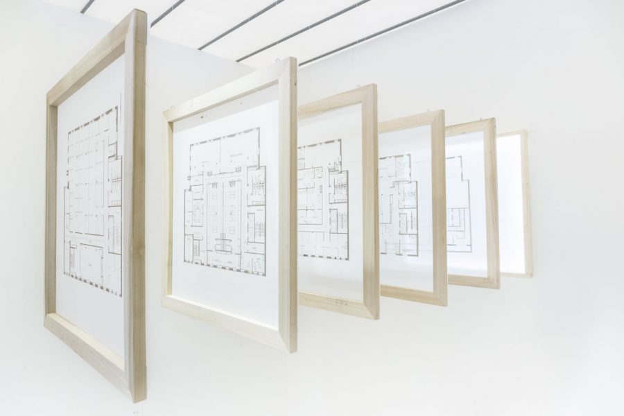 Six hanging wooden frames with black and white floor plans displayed in the center of each frame