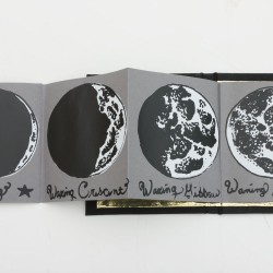 A grey brochure the four phases of the moon from the new moon on the left to the full moon on the right, and each of the four phases has a short text under it.