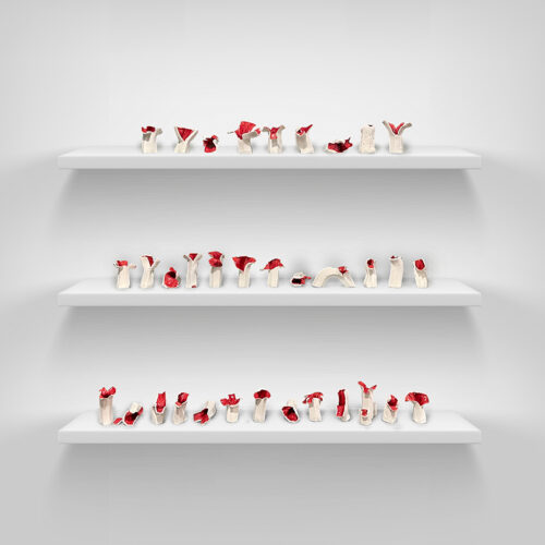 Three shelves are installed on a wall with several ceramic mushrooms placed randomly between the three shelves. The mushrooms have an off-white stem with a red top.