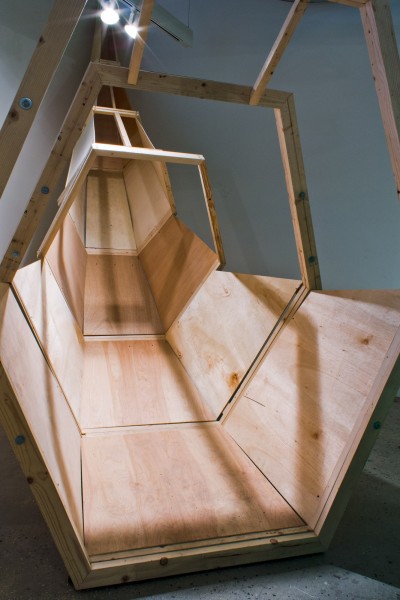 A wooden sculpture in the shape of a slide, made of wood panels.