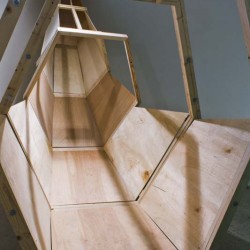 Wood sculpture made of wood boards, wood pieces, in the shape of a slide without top cover