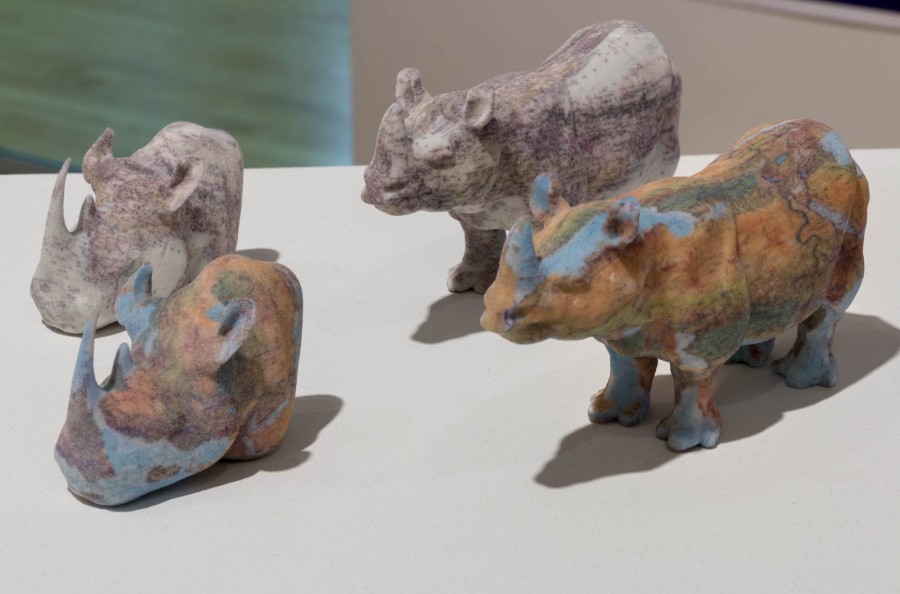 Different angle of four 3D rhinos in pastel colors are placed on a table.