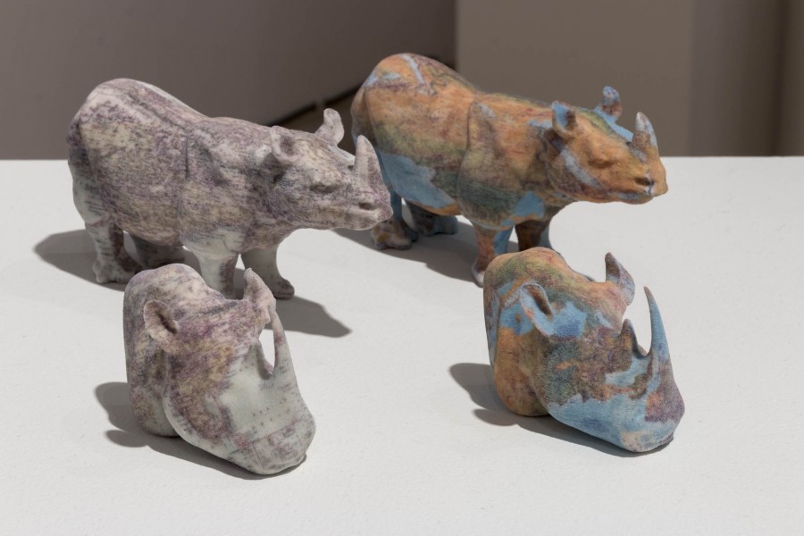 Four 3D rhinos in pastel colors are placed on a table.