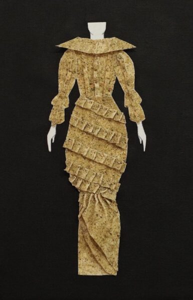 A 2D dress sample by Tiffany Bales depicting a figure wearing a brown dress. The sample is made from unbleached muslin fabric, sand, mold builder, thread, canvas, cardboard, and a body paper cutout. 