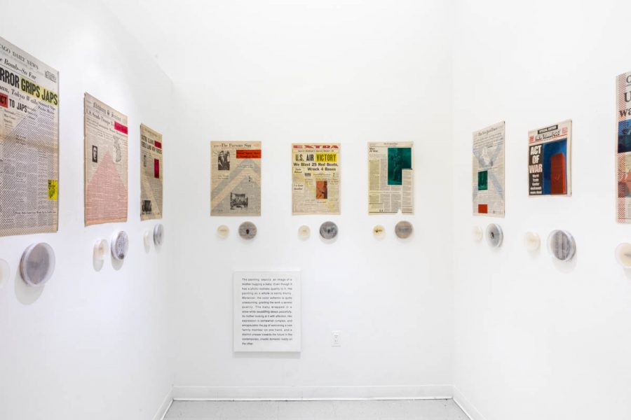 Installation view of newspaper pages glued on the wall and under them are installed rounded recipients with insects and some organic materials