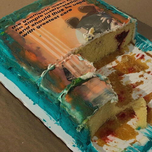 A half eaten cake with an image printed on the surface consisting of an orange background and black text with black designs.
