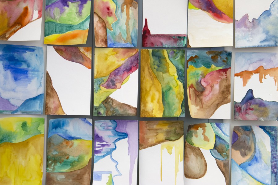 An array of eighteen abstract paintings made with watercolors with colors including orange, brown, green, glue, yellow, etc