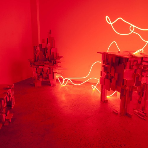 Installation of three sculptures from cubic shapes. The sculpture on the right side has a bright red illuminating neon attached to it. The installation place of the sculptures is enlightened in bright red color.