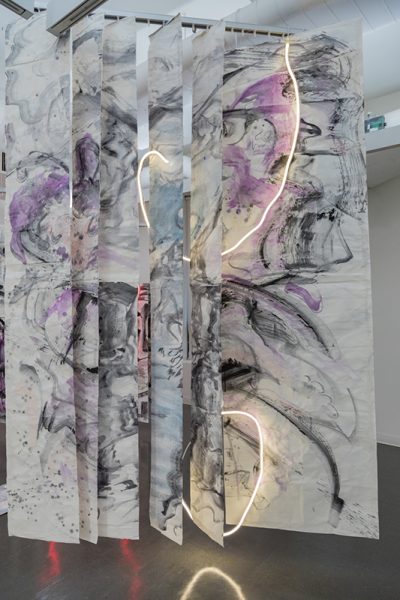 Installation view of artwork by Yesiyu Zhao. Chromatic mixed media artwork with abstract brush strokes, torn fabric interwoven with neon lights.