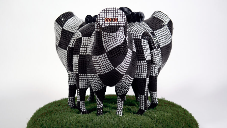 Sculpture of sheep with a mosaic chessboard pattern, one sheep has an LED timer inserted into it's head and there are also visible chess pieces