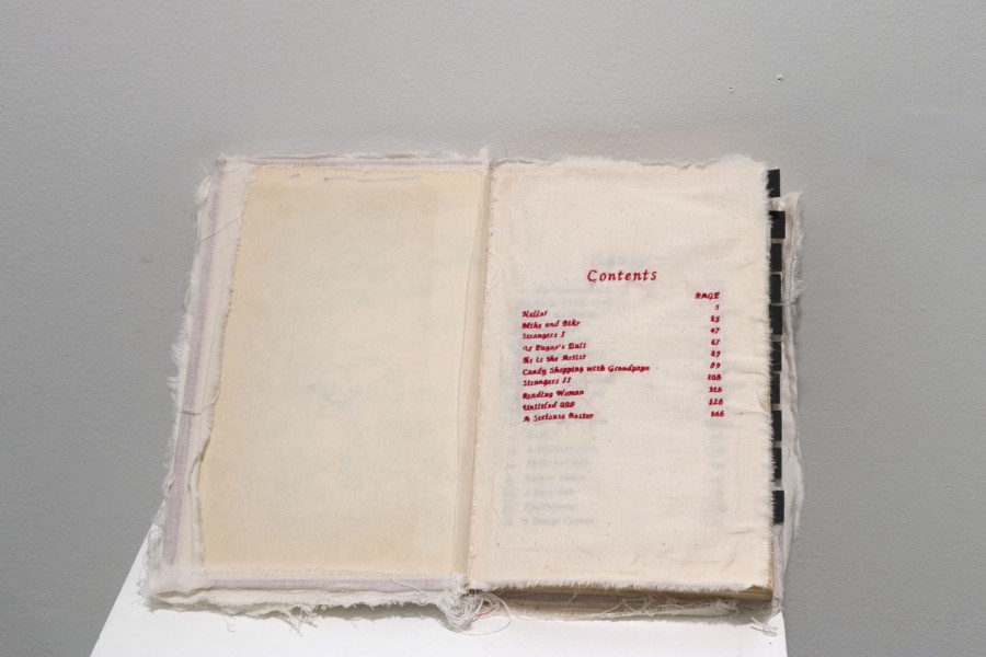 A book with pages made out of fabric and the content table is written with a red embodiment. The book is placed on a stand.