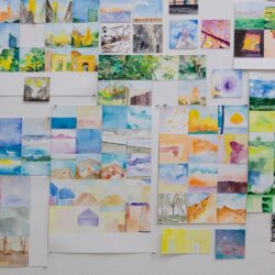 Many small, colorful, square paintings by Zihao Ren crowded together on a white wall in a gridded format.