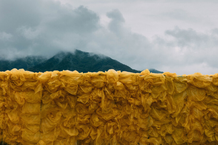 Close-up video still of a large rectangular yellow sculpture of wood and plastic bags installed outdoors