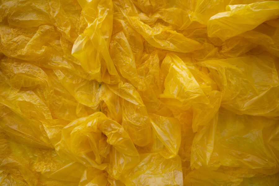 Close-up video still of a large rectangular yellow sculpture of wood and plastic bags