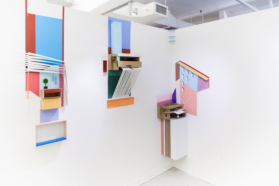 Installation view of vinyl shapes installed on the wall with cardboard shelves and shapes made in the form of a plant in a vase, an outside wall of a building, with blue, red, pink, orange, green, etc.