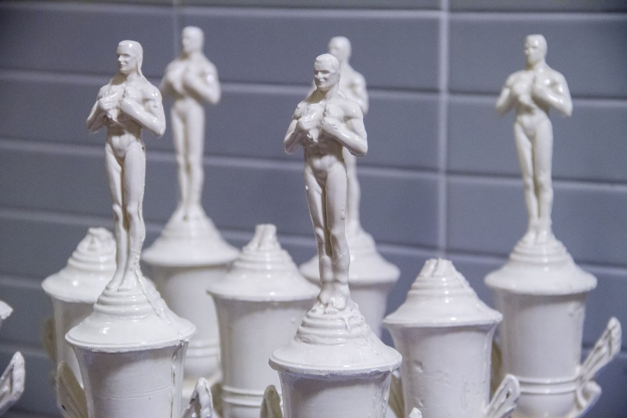 Close image of five ceramic statues of a man on top of white recipients