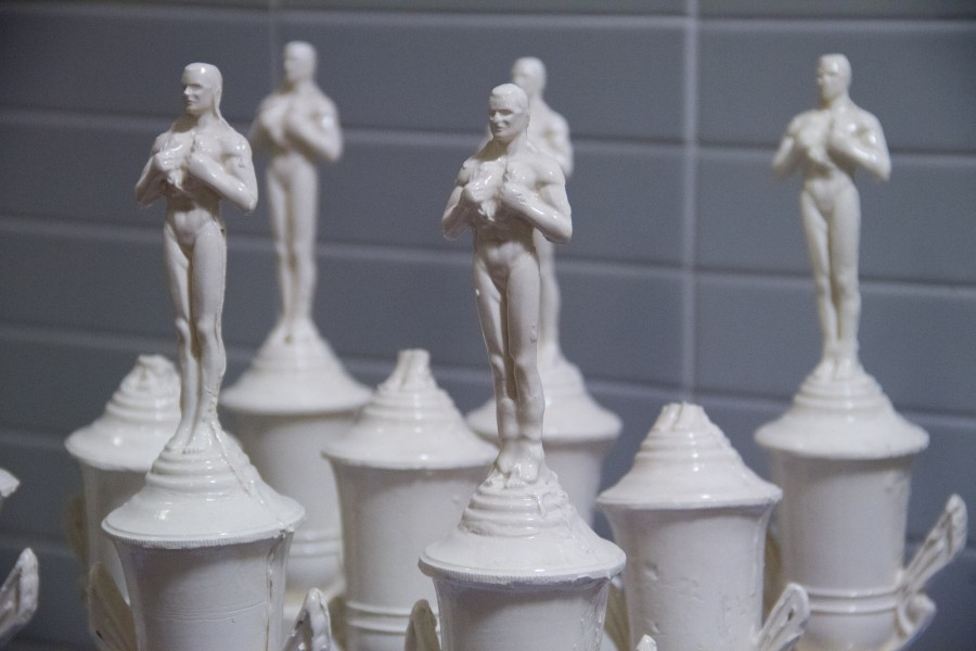 Close image of five ceramic statues of a man on top of white recipients