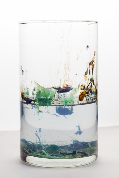 Large rounded container with transparent liquid and floating organic shapes in blue, green, etc.