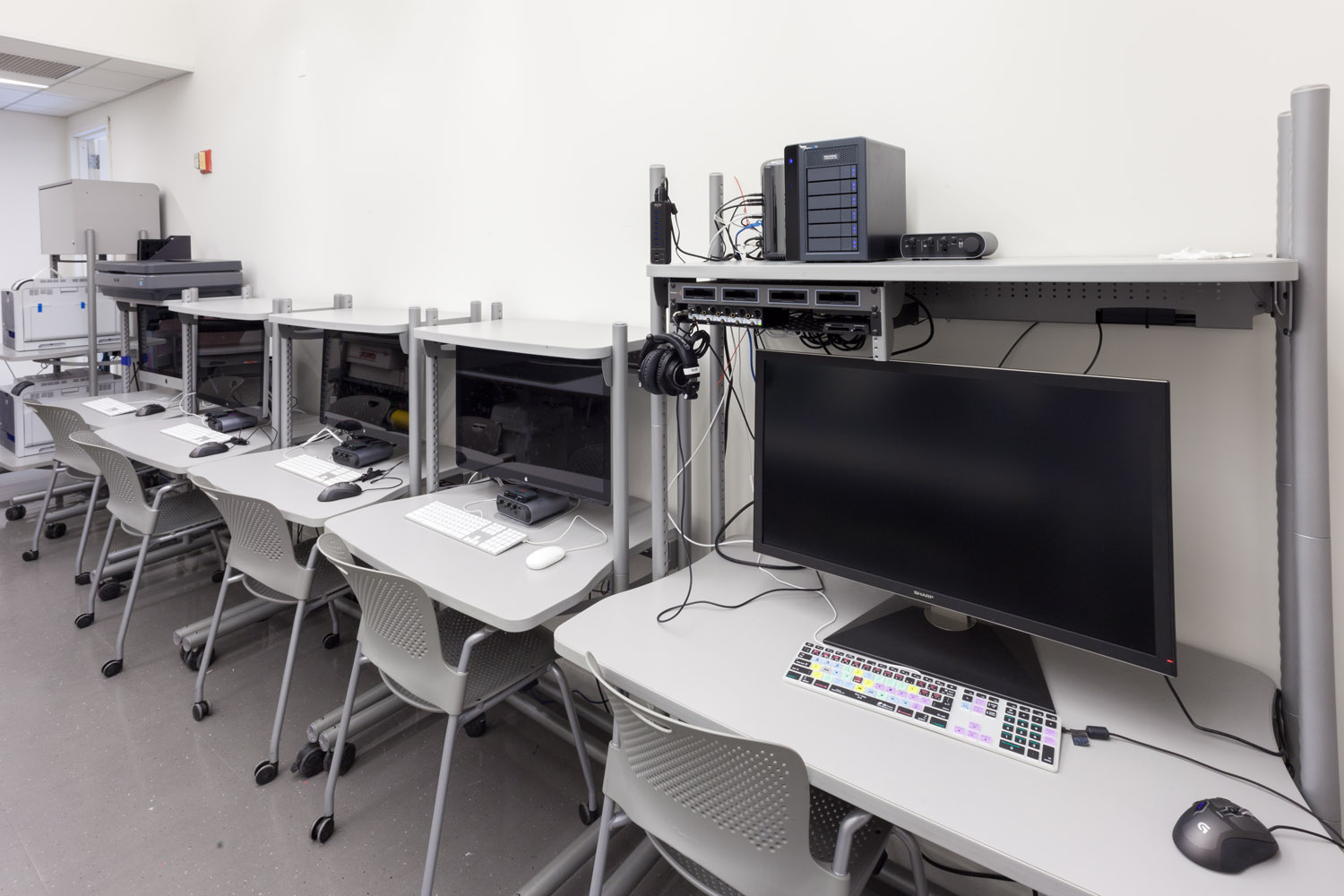 There is a view of the computer lab with computers sitting on desks along the wall.