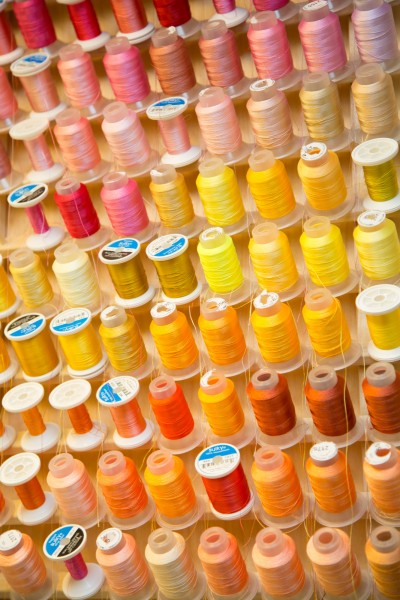Close-up of sewing threads colored from bright red, pink, yellow, to orange