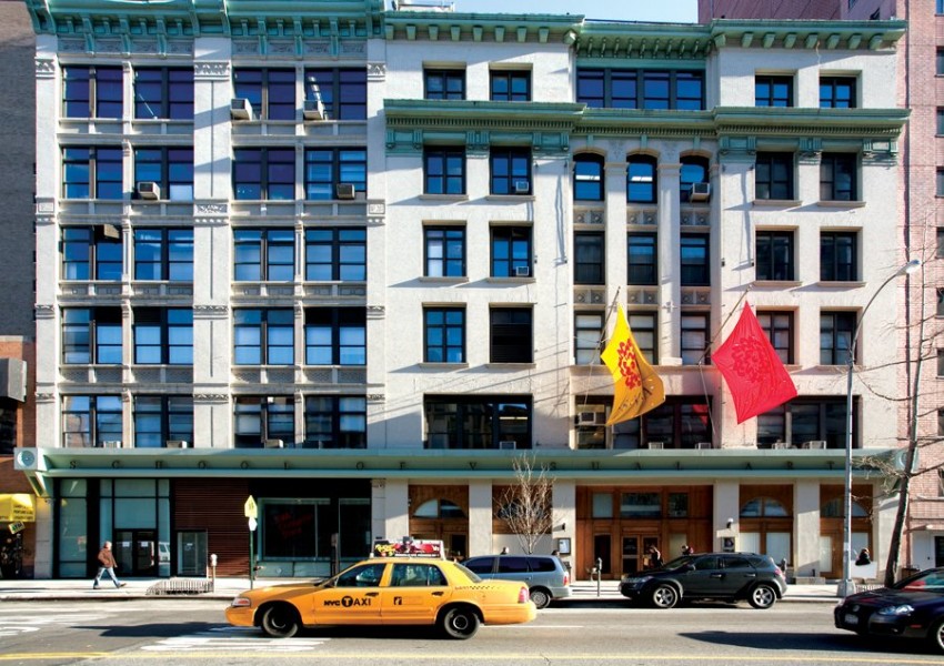 Outside view of SVA building in the light of day at with cars parked in front of it and a yellow cab passing by on the street
