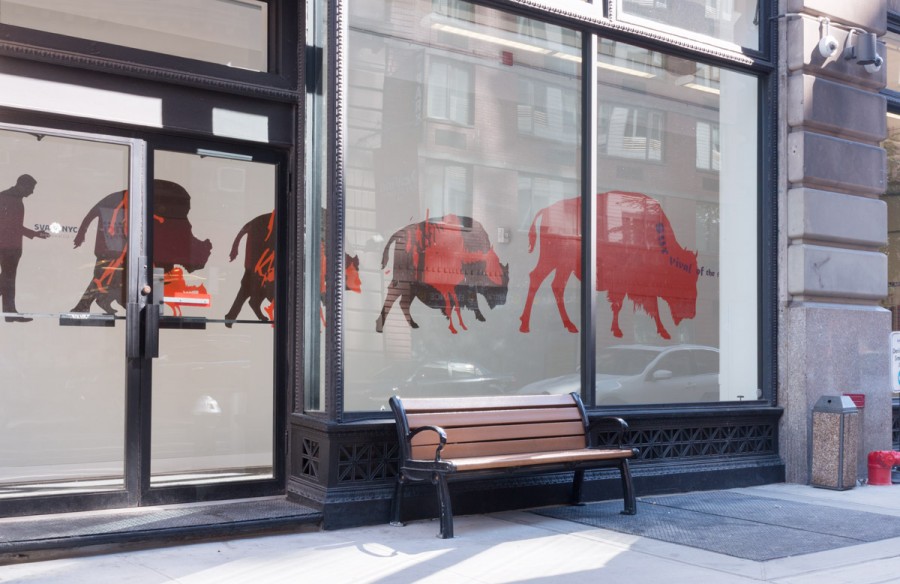 A view of big windows and a door with widows with vinyl shapes in the form of a bull in red and maroon, and near the windows is a brown bench
